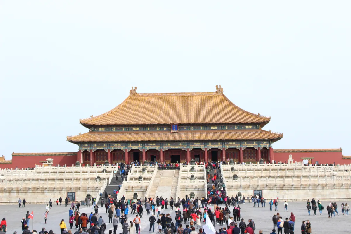 The golden-roofed Hall of Supreme Harmony on its marble terrace in the Forbidden City, Beijing, with crowds of visitors in the plaza below.