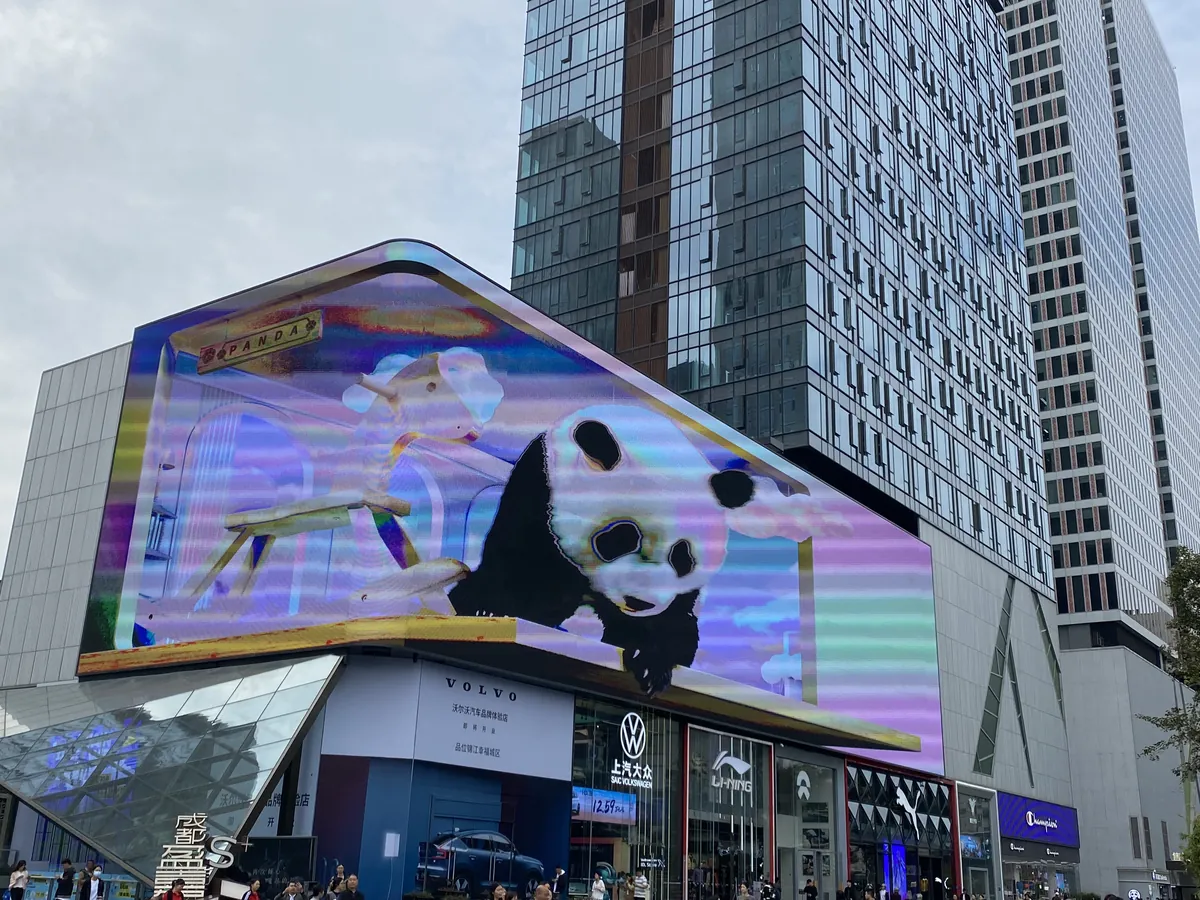 A huge LED billboard with a leaping panda animation above the skyscrapers of Chengdu's Chunxi Road shopping district.